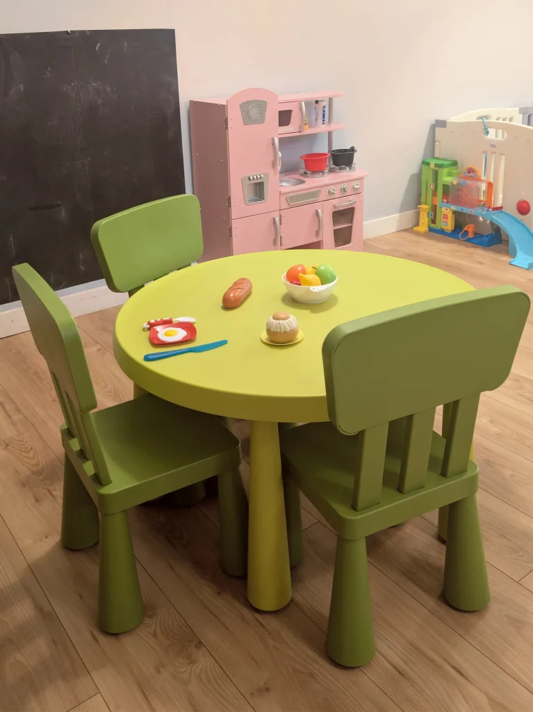 Petite table et chaises vertes pour enfants avec jeux d'imitation (dinette) et tableau noir à la MAM Les Chérubins à Perpignan.