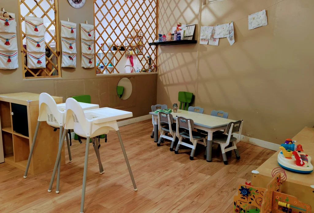 Espace repas aménagé de la MAM Les Chérubins à Perpignan, avec plusieurs chaises hautes autour d'une table adaptée et des rangements individuels pour les enfants.