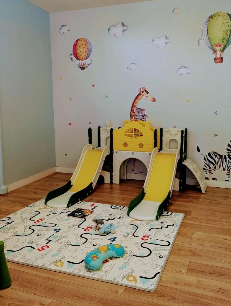 Un petit toboggan pour enfants posé sur un tapis dans la salle de jeux lumineuse de la MAM Les Chérubins à Perpignan.